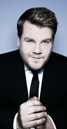 a man in a black suit and tie posing for a photo with his hands on his chest