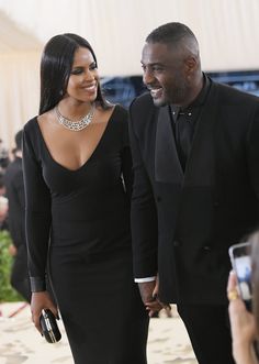 a man and woman in formal wear walking down the red carpet at an event together