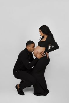 a man kneeling down to kiss a pregnant woman's belly in front of a white background