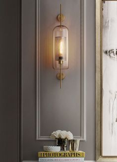 a white table topped with a vase filled with flowers next to a wall mounted light