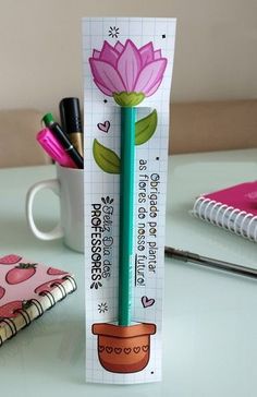 a pencil holder with a flower on it sitting next to a notepad and pen