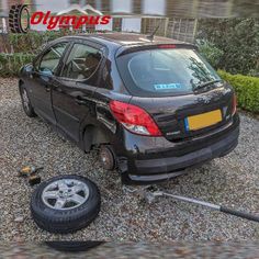 a small black car parked in front of a house with the word olypgus on it