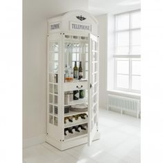 a tall white cabinet with wine bottles in it's glass doors and the door open