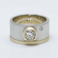 two tone gold and silver wedding ring with a diamond set in the center, on a white background