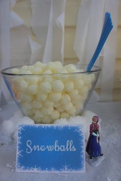 a bowl filled with white candy next to a small figurine holding a blue toothbrush