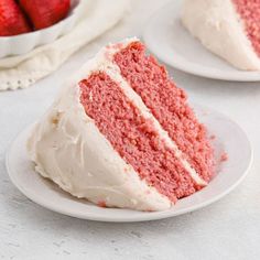 a slice of red velvet cake with white frosting and strawberries in the background