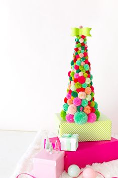 a christmas tree made out of pom poms on top of pink and green boxes