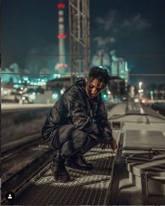 a man squatting on the side of a train track