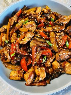 a bowl filled with chicken and vegetables covered in sesame seeds