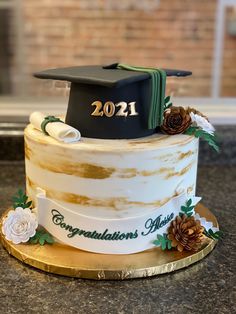 a graduation cake decorated with gold and white frosting