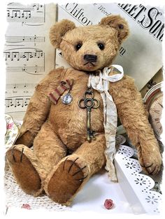 a brown teddy bear sitting on top of a table next to music sheets and keys