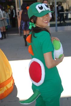 a woman in a green costume holding a ball and wearing a frog costume on her head