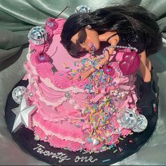 a barbie doll cake with pink frosting and sprinkles