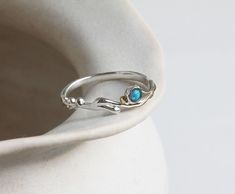 Invoking the gentle summer waves off the Devon coast, this dainty ring features a blue Fire Opal and is finished with our signature 14kt gold details, set on a curving Sterling Silver band crafted from our unique wax form.  Perfect for anyone with an appreciation of coastal jewellery. The graceful intricacy of the design combined with Opal, which is known to be an October birthstone, creates a thoughtful personalised gift. Designed in our Devon studio, our ring is handcrafted with the utmost car Coastal Jewelry, Slim Ring, Blue Opal Ring, Jewellery Unique, Zierlicher Ring, Coastal Blue, Jewellery Handmade, Funky Jewelry, Ocean Lover