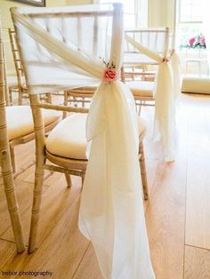 the chairs are decorated with white ribbons and flower arrangements for an elegant touch to the room