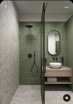 a green tiled bathroom with a shower, sink and stand - up shower head mounted on the wall