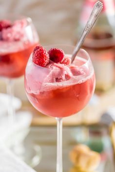 two glasses filled with raspberry ice cream and topped with fresh raspberries