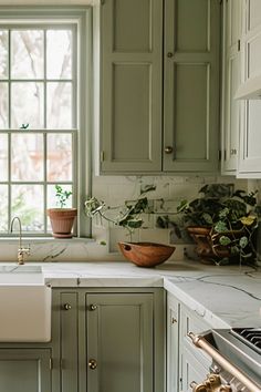 a kitchen with green cabinets and white counter tops, an oven, sink and window