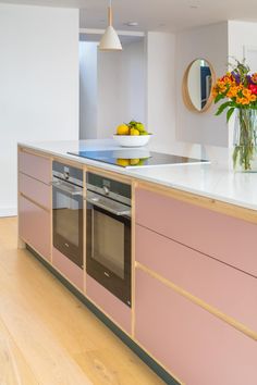 a kitchen with pink cabinets and white counter tops