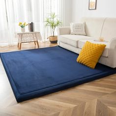 a living room with a blue rug on the floor and a white couch in front of it