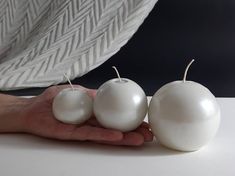 three white apples sitting on top of a table next to a person's hand