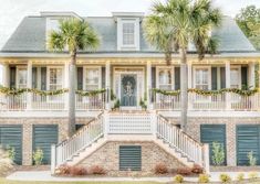 a house with shutters and palm trees on the front porch is decorated for christmas