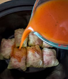 someone pouring sauce onto some food in a slow cooker