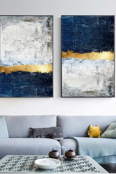 two paintings on the wall above a couch in a living room with blue and yellow accents