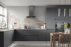 a modern kitchen with grey cabinets and wooden table in front of the stove top oven