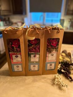 two brown bags sitting on top of a counter covered in flowers and ribbons with tags attached to them