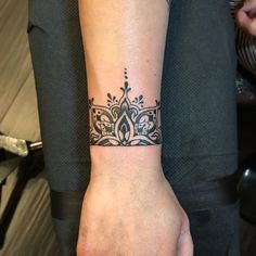 a woman's arm with a tattoo on it and a wristband in the shape of a crown