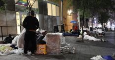 a man standing on the sidewalk next to trash bags