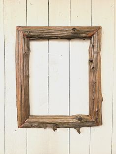 an old wooden frame hanging on a white painted wall with wood planks in the background