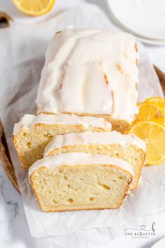 a loaf of lemon pound cake sitting on top of a piece of wax paper next to sliced lemons