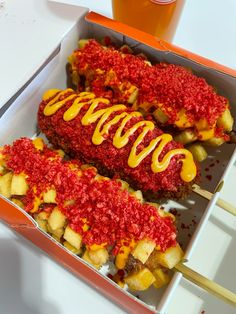 two hot dogs in a box with ketchup and mustard drizzled on them