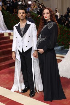 a man and woman standing next to each other in front of a red carpeted area