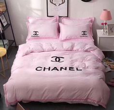 a pink bed with chanel logo on the comforter and two pillows in front of it