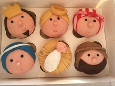 six cupcakes in the shape of people wearing hats and holding a baby jesus