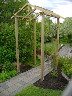 an outdoor garden with a trellis, walkway and wooden structure in the middle of it