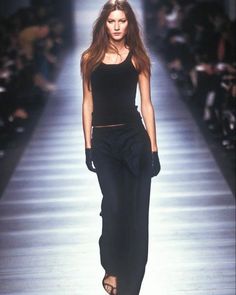 a woman walking down a runway in black