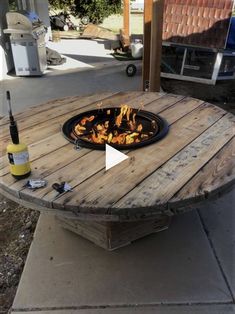 a wooden table with a fire pit on it and a bottle of wine in the middle