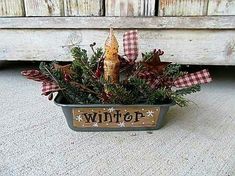 a potted plant with a wooden sign that says winter on it and pine cones