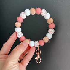 a person holding onto a bracelet made out of beads and wooden beads with a gold charm