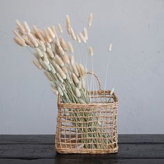 a wicker basket filled with dried flowers on top of a wooden table