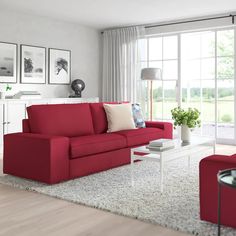 a living room with red couches and white rugs on the floor in front of large windows