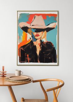 a painting hanging on the wall next to a table with a cup and saucer