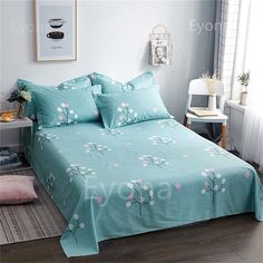 a bed with blue sheets and pink flowers on it in a room next to a window