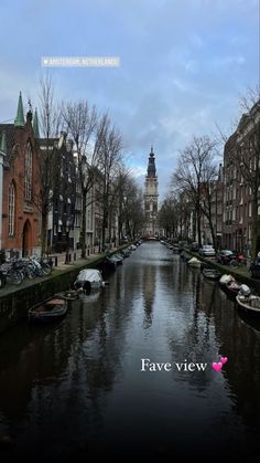 a river running through a city with buildings on both sides and a clock tower in the distance