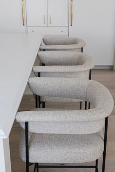 a row of chairs sitting on top of a wooden floor next to a white counter