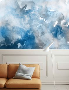 a couch in front of a wall painted with blue and white watercolors